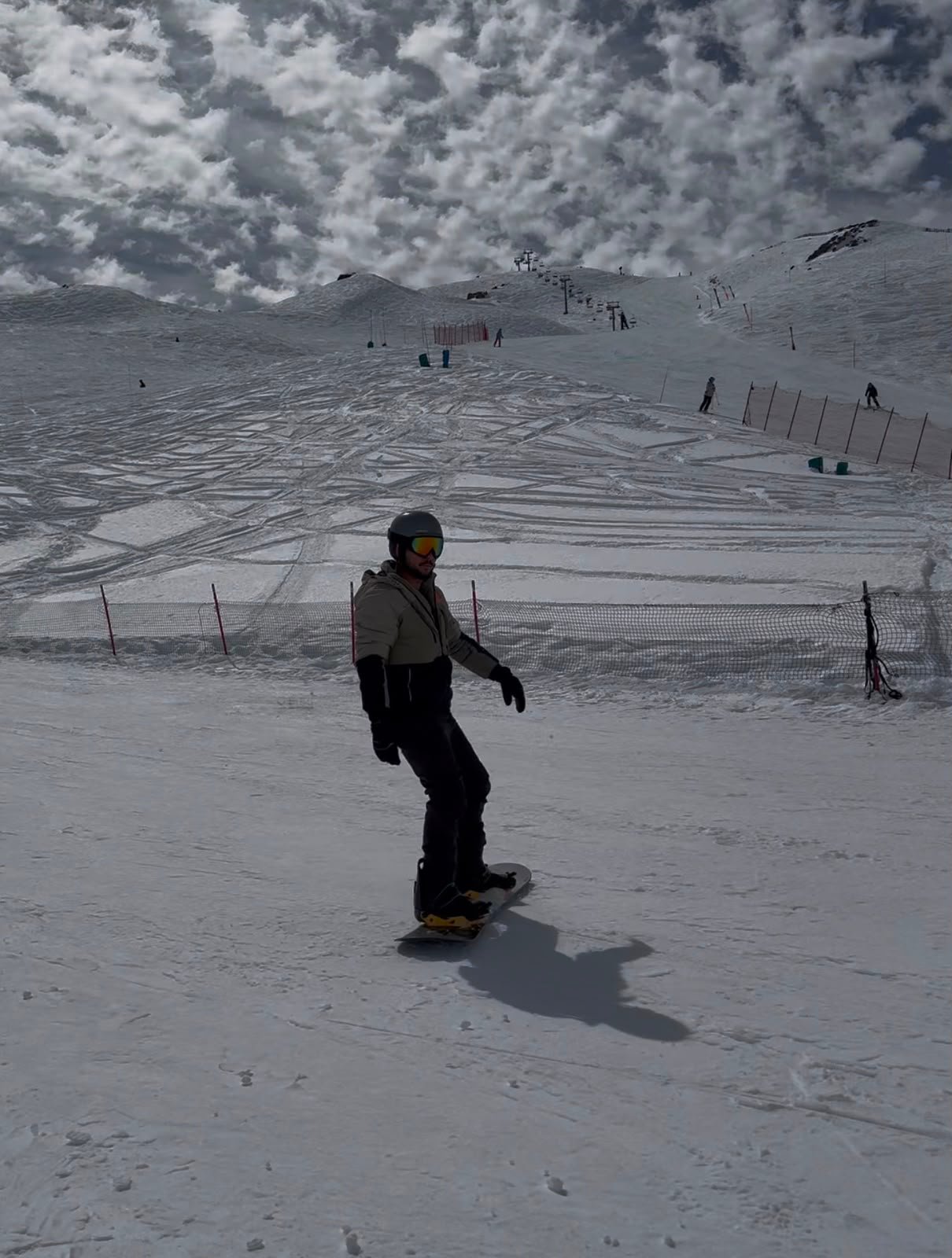Homem praticando snowboard em uma pista de neve sob céu nublado, representando liberdade e aventura