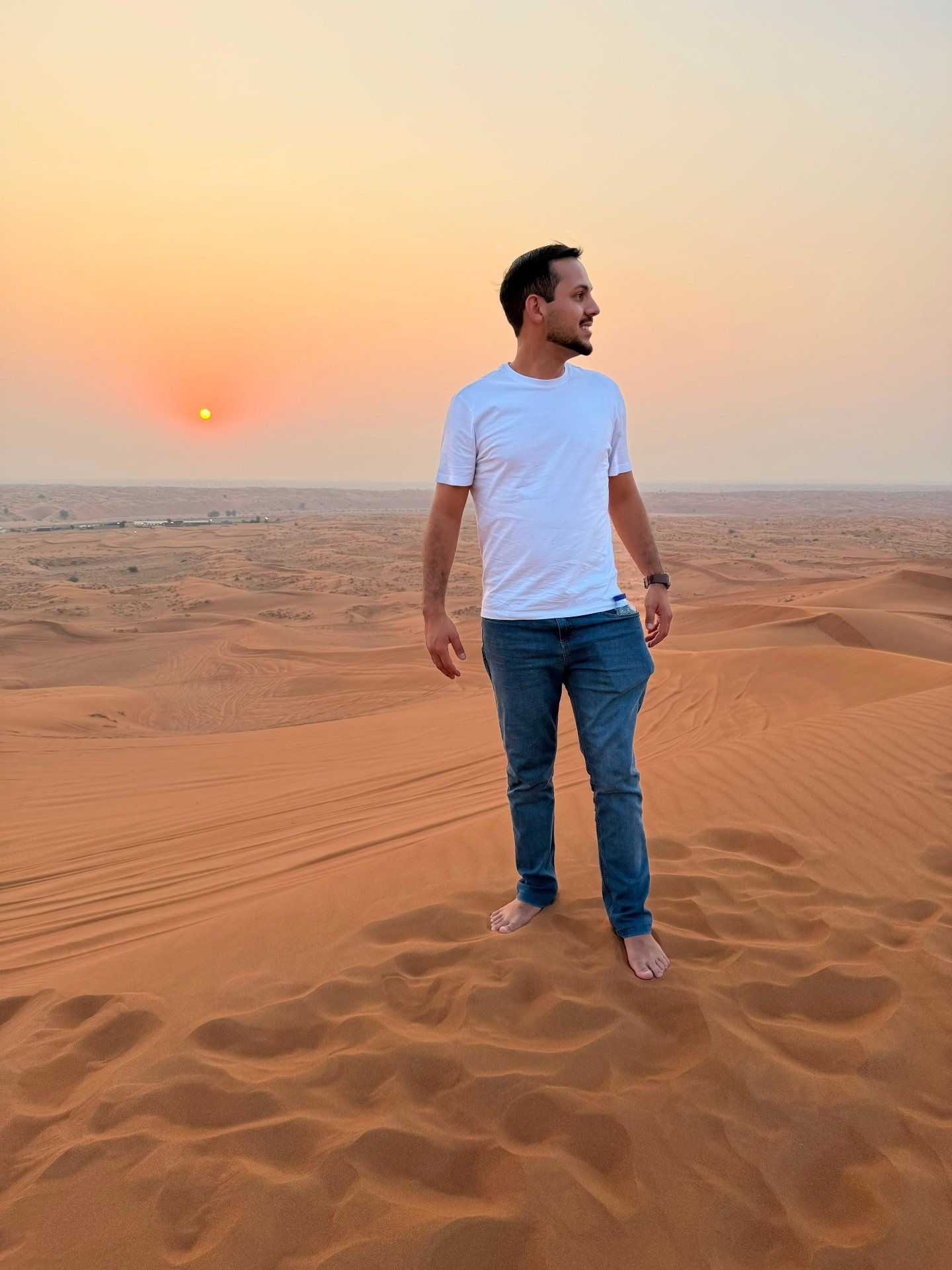 Homem em pé sobre dunas de areia ao pôr do sol, simbolizando liberdade e novas possibilidades
